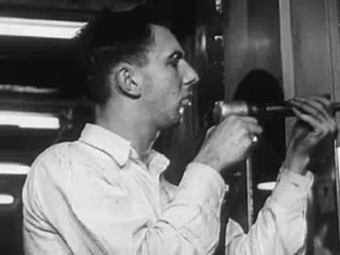 Male factory worker using a pneumatic tool on metal part