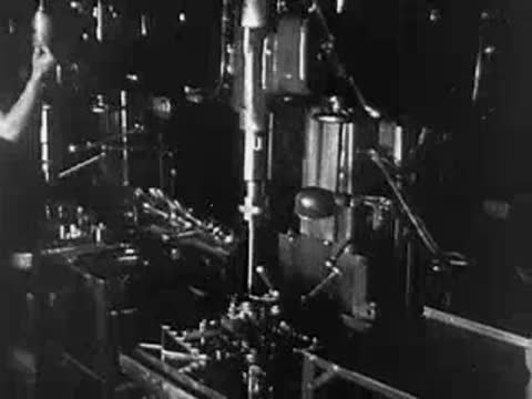 Industrial interior with worker operating machinery and drill presses