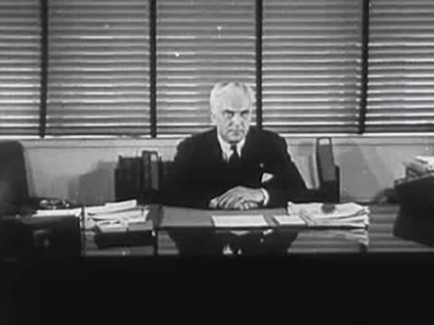 Man in suit sitting behind a desk with office documents