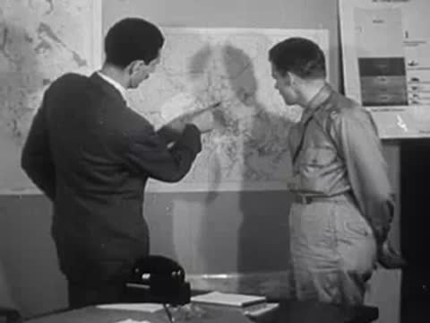 Two men pointing at a wall map in an office