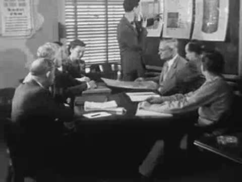 Meeting in a conference room with charts and several seated people