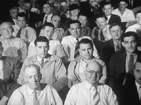 Audience seated in an auditorium listening attentively, vintage clothing.