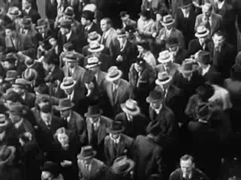 Dense crowd of people walking outdoors, World War II era fashion