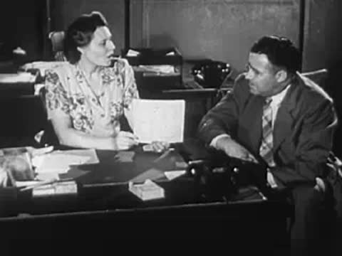 A woman and a man seated across a desk in an office.