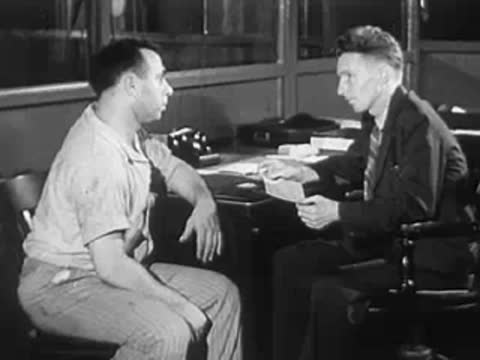 Two men sitting in an office or control room having a conversation.