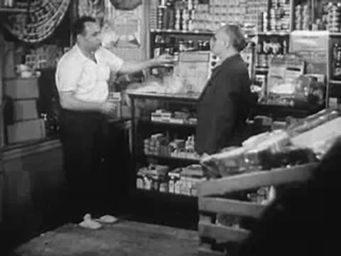 A worker behind a store counter interacting with a customer in shop.