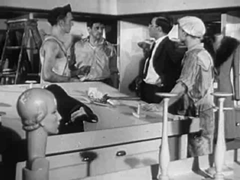Men working in a workshop or factory with mannequins nearby.