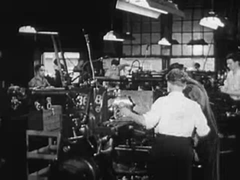 Workers operating machinery in a busy industrial manufacturing plant.
