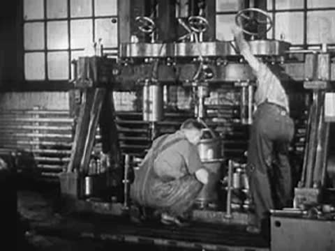 Workers operating a large industrial press or machinery in factory.