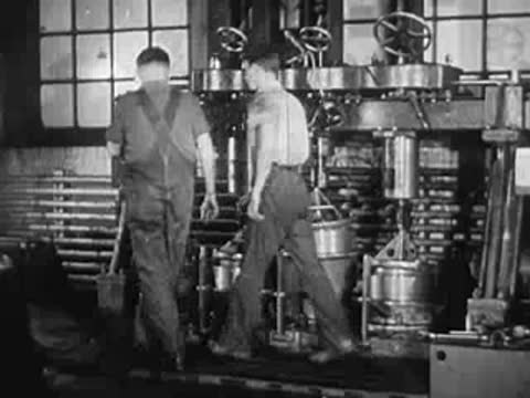 Two workers walking away from a large industrial machine in factory.