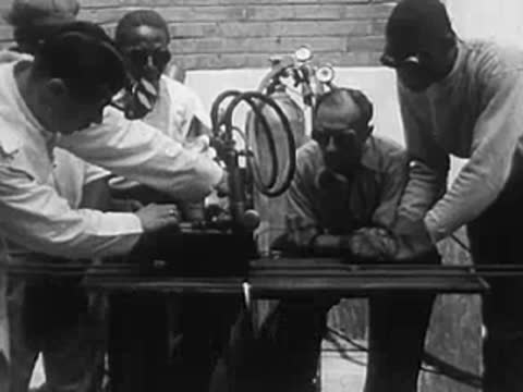 Workers operating welding equipment with sparks in an industrial setting.
