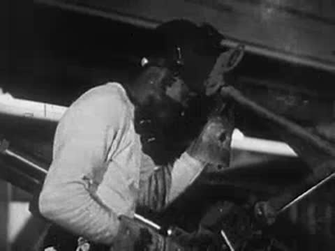 A welder in protective gear working with sparks flying in an industrial setting.
