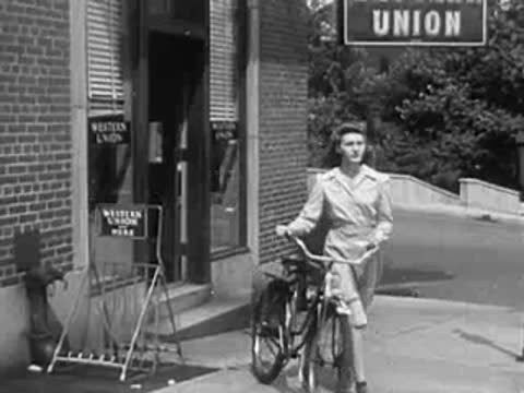 A woman with a bicycle outside a Western Union office.