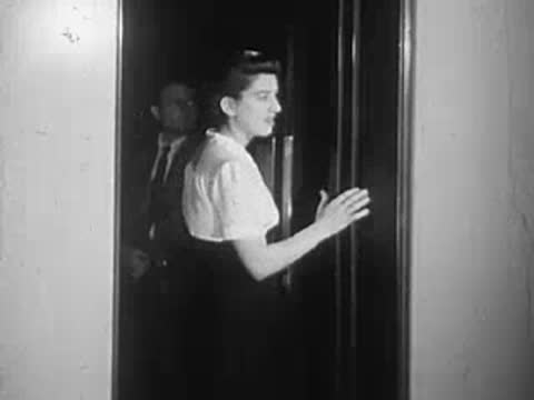 A woman holding a cup walking through a doorway inside a building.