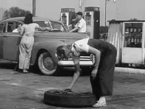 A mechanic working on a car tire at a service station.