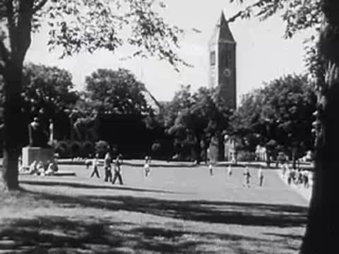 Exterior view of university campus quad with people walking, historic clock tower