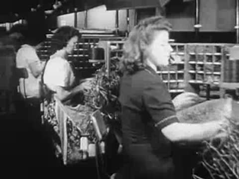 Women working at desks sorting or assembling materials in a factory.