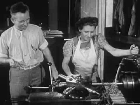 A man and woman operating heavy machinery in an industrial workshop.
