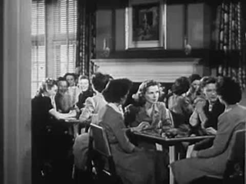 Group of women sitting at tables indoors, WWII era setting