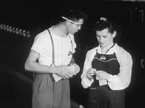 A man and woman standing together in a factory setting talking.