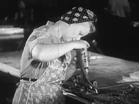 Woman with headscarf operates a drilling machine at a workbench, assembly line