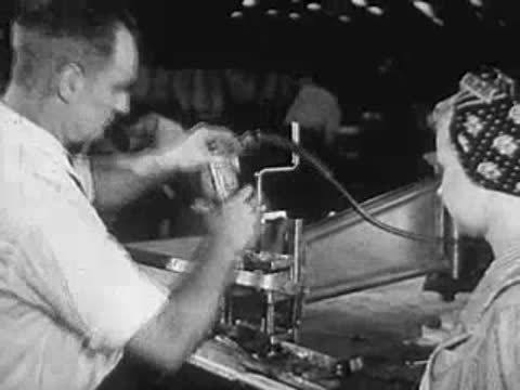 Man and woman working on assembly lines with machinery, factory setting