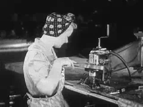 Workers operating industrial equipment along an assembly line in a factory