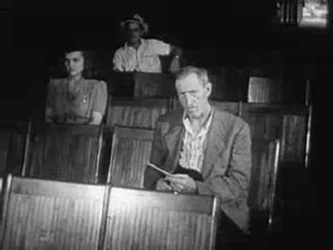 Crowd of people in a meeting hall, man reading a document