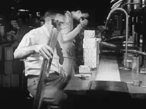 Worker handling long tubes on a factory assembly line