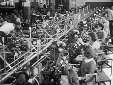 Busy factory interior with extensive machinery and workers along production lines