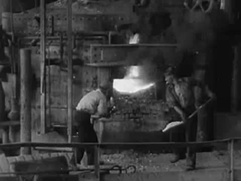 Workers operating a large industrial furnace in a metalworking foundry