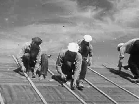 Industrial workers performing tasks in a factory, followed by construction workers laying roof panels outdoors.
