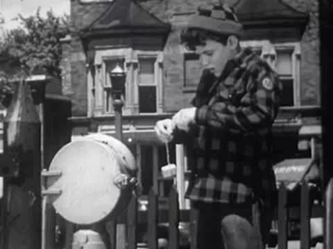 Boy opening a small package hanging from a white container on a post.
