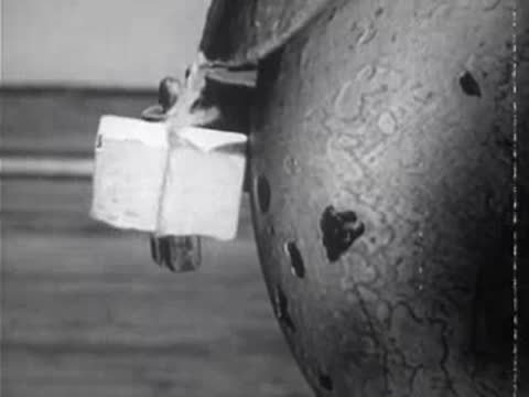 Close-up of a small wrapped package hanging from a white container on a post.
