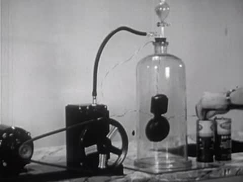 Vacuum pump system connected to a glass bell jar on a laboratory table.