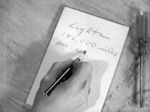 close-up of hand writing light speed on paper
