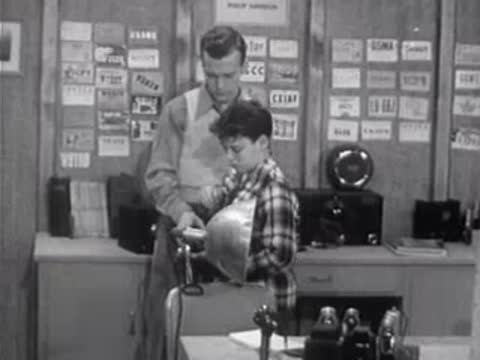 Instructor showing boy parabolic reflector in classroom with educational wall displays