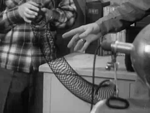 Hand attaching black mesh cord to spring coil apparatus in laboratory