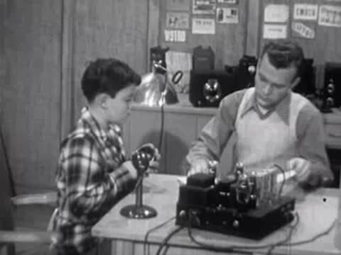 Boy and instructor working with electronic device on desk in laboratory