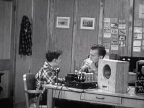 Boy and instructor seated at desk with scientific equipment in laboratory