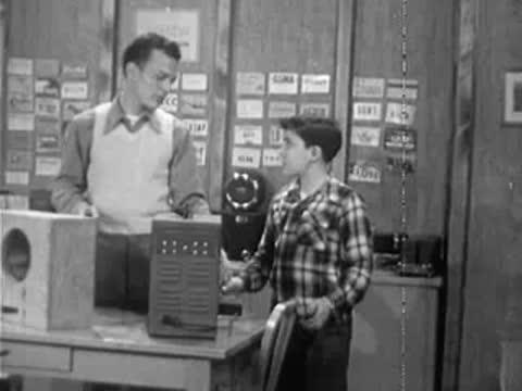 Instructor placing scientific electronic equipment on desk next to boy