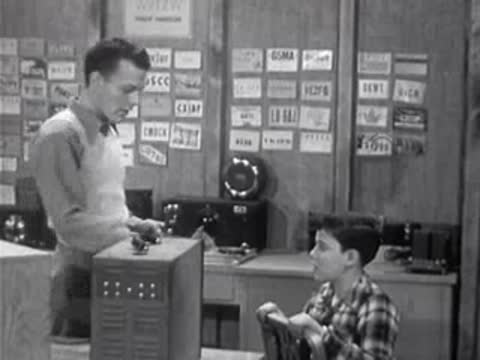 Instructor and boy interacting near electronic equipment on desk
