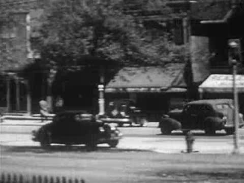 City street scene with cars, trees, and buildings on a bright day.