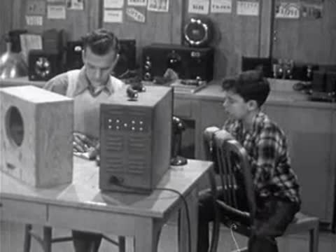 Instructor writing notes at laboratory desk while boy watches