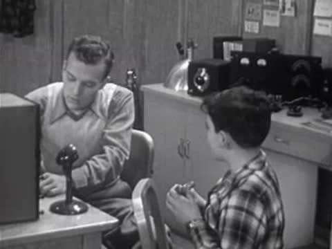 adult teaching a boy in a room with vintage electronic equipment