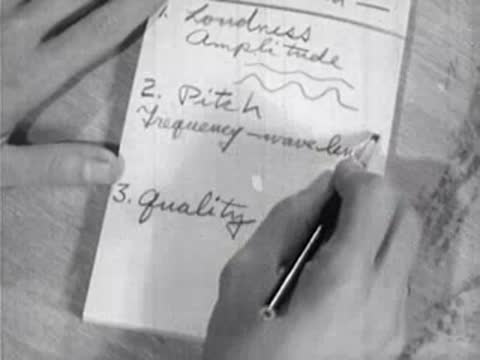 hands writing science notes about sound in a notebook