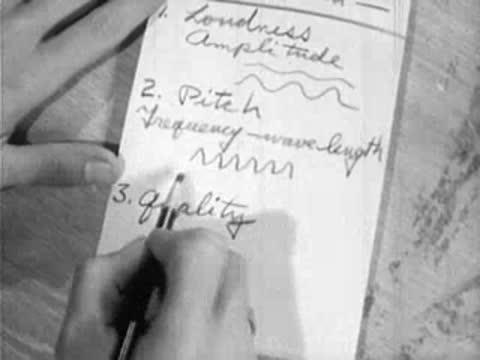 hands writing science notes about sound in a notebook