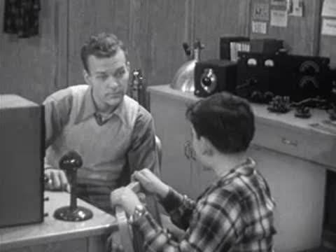 adult teaching a boy in a room with vintage electronic equipment