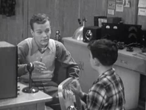 adult teaching a boy in a room with vintage electronic equipment