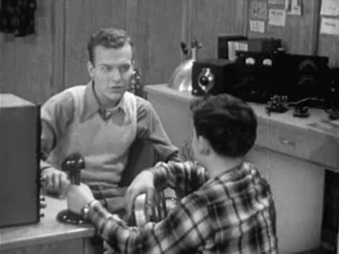 adult teaching a boy in a room with vintage electronic equipment